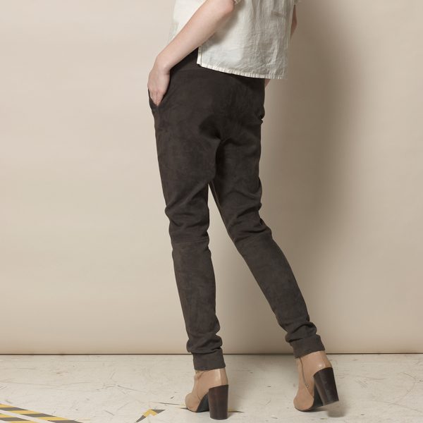 Legs of a woman in brown velor leather pants in jogger style from the side